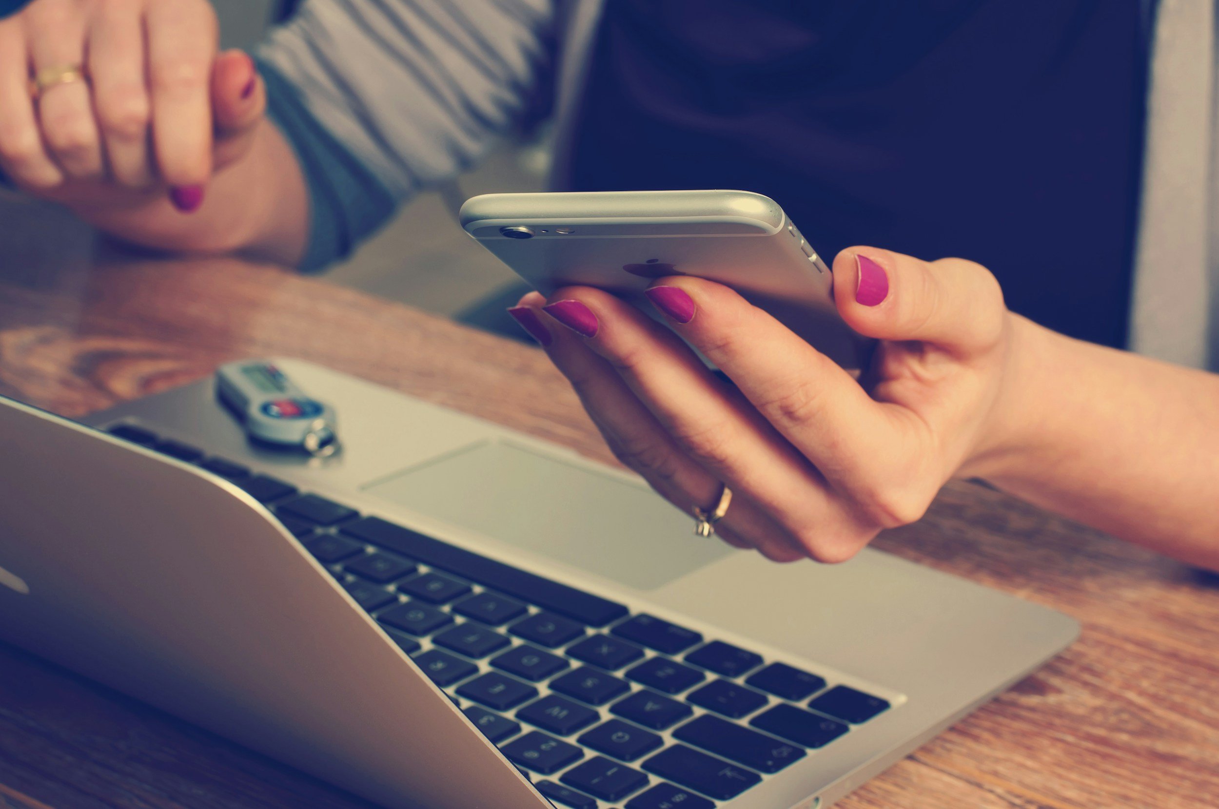Broker holding mobile phone above keyboard